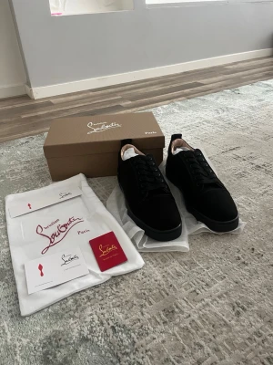 Svarta sneakers från Christian Louboutin - Snygga svarta sneakers från Christian Louboutin med klassisk låg siluett. Skorna har svart ovandel i mocka och läder, svarta skosnören och diskret design. Perfekta för dig som gillar stilrena och exklusiva sneakers.