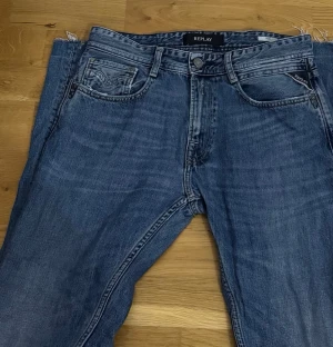 Blå raka jeans från Replay 30/32 - Säljer ett par klassiska blå jeans från Replay med raka ben och fem fickor. Jeansen har en snygg tvättad look och detaljerade sömmar på bakfickorna. Perfekta för en avslappnad stil och tillverkade i slitstarkt denimtyg. Jeansen har en ”flared” kant vid fötterna (se bild 3)