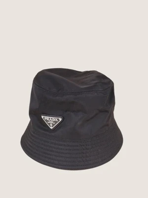 Svart bucket hat från Prada - Snygg svart bucket hat från Prada i nylon med den ikoniska trekantiga logotypen framtill. Klassisk form med bredare brätte och stilren design som passar till streetwear och trendiga outfits.