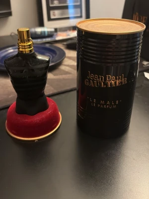 Jean Paul Gaultier Le Male Parfym - Säljer en Jean Paul Gaultier Le Male Le Parfum i en snygg svart flaska formad som en manlig torso med guldfärgad spraykork. Flaskan har mattsvart finish med blanka ränder och kommer med originalförpackning i svart metall med gulddetaljer. 75 ml flaska med runt 50 ml kvar