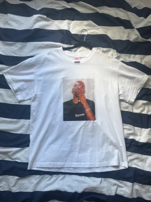Supreme Dean Blunt tee - Medium - Säljer en vit t-shirt från Supreme med ett stort tryck på bröstet som föreställer en person som röker. T-shirten har rund hals och korta ärmar. Perfekt för dig som gillar streetwear och vill sticka ut med en ikonisk design.