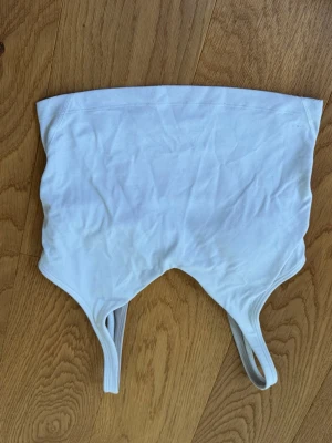 Vit sport-bh från Lululemon - Säljer en vit sport-bh från Lululemon med smala axelband och stretchigt material. Perfekt för träning eller yoga. Enkel och stilren design med diskret logga på ryggen. Sitter tajt och ger bra stöd under aktivitet.