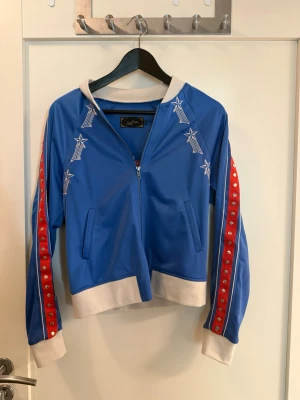NON SENSE RARE EMBROIDERED BOMBER 💙❤️ - Så cool och ovanlig statement-jacka från svenska Non Sense – märket skapat av Per Holknekt & Karin Jimfelt-Ghatan (duon bakom Odd Molly).  Klarblå bomber med röda/vita detaljer, silverfärgade studs längs hela ärmarna + fantastiska broderier fram och ett stort broderat motiv över ryggen.   Köpt för länge sedan men bara använd ett fåtal gånger – har mest hängt i garderoben. Svår att hitta idag! ⭐ Y2K / rock chic / statement / retro