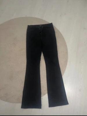 Svarta bootcut jeans - Snygga svarta bootcut jeans med klassisk femficksdesign och hög midja. Jeansen har utsvängda ben och är tillverkade i ett mjukt denimtyg som ger en skön passform. Perfekta för dig som gillar en retroinspirerad look.