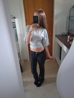 Grå croppad t-shirt - Säljer en enkel och stilren grå croppad t-shirt med korta ärmar och rund hals. Perfekt till jeans eller kjol för en avslappnad look. Materialet känns mjukt och bekvämt, troligen bomull eller en bomullsblandning.💕