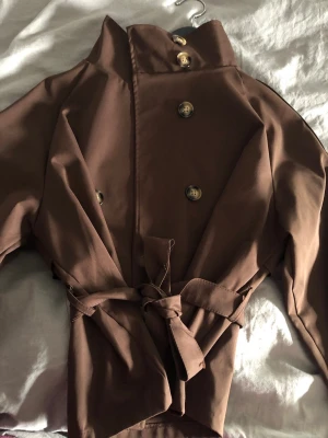 Brun trenchcoat med knytskärp - Köpt för några år sedan, aldrig använd. Storlek S