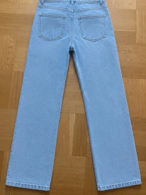 Ljusblå baggy raka jeans med slits - Säljer ett par ljusblå jeans med rak baggy passform och hög midja. Jeansen har klassiska bakfickor och en liten slits längst ner på framsidan av benen. .