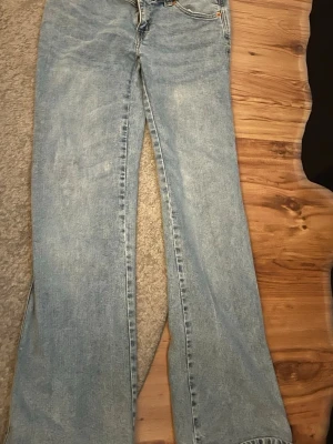 Ljusblå utsvängda jeans från 157 - Säljer ett par ljusblå jeans från 157 med utsvängda ben och klassisk femficksmodell. Jeansen har en avslappnad passform och är gjorda i denim med synliga sömmar. Perfekta för en trendig och bekväm look.