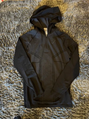 OG Svart Gymshark onyx v3 hoodie ÄKTA och sällsynt - Snygg svart Gymshark onyx v3 hoodie med halv dragkedja och diskret mönster på bröst och rygg. Långärmad modell med åtsittande passform och huva. Perfekt för dig som gillar sportig och stilren look. Materialet känns mjukt och stretchigt. Otroligt sällsynt och tillverkas ej längre, inga tecken på användning. Priset kan diskuteras! Kontakta vid frågor!