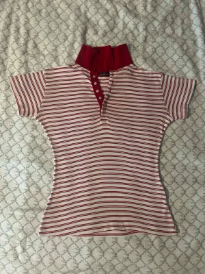 Brandy Melville polo top - Säljer en söt polotopp med röda och vita ränder samt en, röd krage. Figurnära passform och ett sportigt, retroinspirerat uttryck. 100% bomull. Jättefint skick!💕 