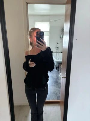 Svart off shoulder tröja - Snygg svart off shoulder tröja med avslappnad passform och långa ärmar. Perfekt för dig som gillar en trendig och bekväm stil. Tröjan har en bred halsringning som kan bäras nedhasad över ena axeln.