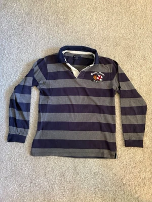 Hackett London Rugby (M) - Klassisk rugbytröja från Hackett London i fint skick. Broderade detaljer och premiumkvalitet. Mindre missfärgning på insidan av kragen som inte syns när kragen är nedvikt (se bild).  📦 Skickas snabbt!