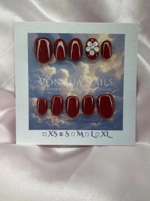 Daisy Red (S);ExtraShortOval  - Snygga handgjorda vinröda press-on naglar i extra kort oval form med vita detaljer och en 3D-blomma på en nagel. Handgjorda och perfekta för dig som vill ha en unik look. Kommer i storlek XS och har en glansig finish.
