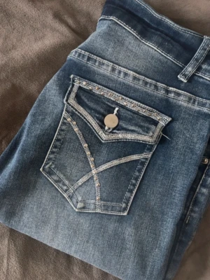 Blå jeans med detaljerad bakficka - Säljer ett par blå jeans med snygg tvätt och unika sömmar på bakfickan i super bra skick kommer inte till användning 💕