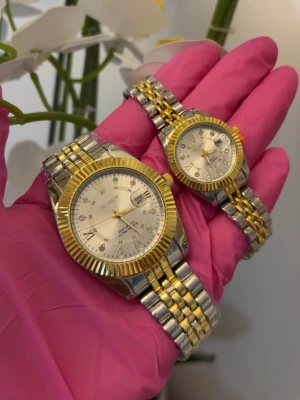 Guld- och silverfärgade parklockor  - Två stilrena parklockor med klassisk rund urtavla i silver och guldfärgade detaljer. Armbandet är i tvåtonad metall, silver och guld, och urtavlan har datumvisning samt markerade timmar. Perfekt för dig som gillar en lyxig och tidlös look. 