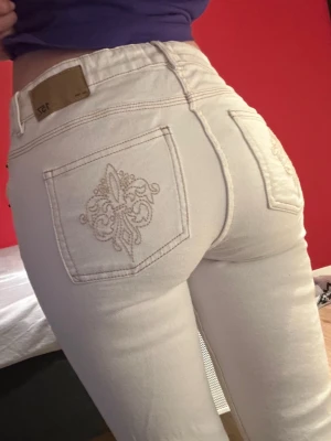 Vita jeans med broderade bakfickor - Säljer ett par vita jeans med snygg broderad detalj på bakfickorna. Bootcut och låg midja. Använda en gång men säljer eftersom dom inte helt är min stil och inte kommer till någon användning.