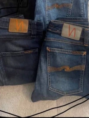 Blå jeans från Nudie Jeans - Säljer flera par klassiska blå jeans från Nudie Jeans med ikoniska bakfickor och kontrastsömmar. Jeansen har normal passform och är tillverkade i slitstarkt denimtyg. Perfekta för dig som gillar en tidlös och avslappnad stil.