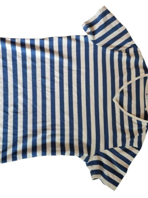 Randig Kvalitéts t-shirt - Säljer en klassisk t-shirt från Bläck med blå och vita horisontella ränder. Tillverkad i mjuk bomull som känns skön mot huden. Har tyvärr en liten fläck mitt på tröjan men inget som inte går bort i tvätten. Perfekt för en niche sommar☀️