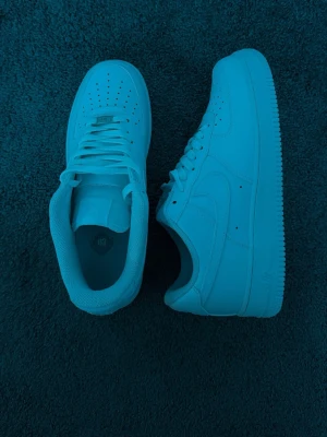Air forces - Säljer ett par vita sneakers med lågt skaft och stilren design. Skorna har perforerade detaljer på tån, vita skosnören och en tjock sula. Perfekta för dig som gillar en clean och tidlös look.