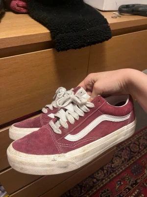 Vinröda Vans 38 - Säljer ett par klassiska Vans Old Skool sneakers i vinrött mockaliknande material med vita detaljer och vit sula. Skorna har den ikoniska vita sidan och vita skosnören. Perfekta för en avslappnad och cool stil.