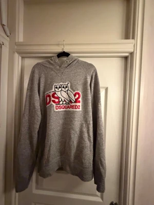Grå hoodie från Dsquared2 med uggla - Säljer en grå hoodie från Dsquared2 i storlek M. Det är lite slitningar på trädarna.