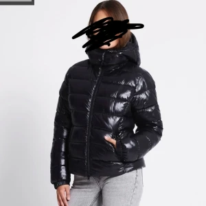Svart pufferjacka med huva - Säljer en svart, glansig pufferjacka med huva och dragkedja framtill. Använd 1 månad under vintern, Inga defekter. Storlek S