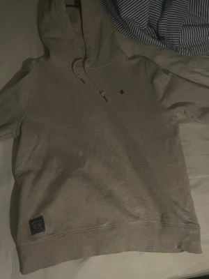 Beige hoodie med patch och huva - Säljer en beige Morris hoodie som är perfekt nu inför hösten då de blir lite kallare för hoodien håller värme bra. Perfekt för en avslappnad stil. Pris kan diskuteras 