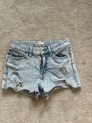 Ljusblå slitna jeansshorts - Säljer ett par ljusblå jeansshorts med slitna detaljer.