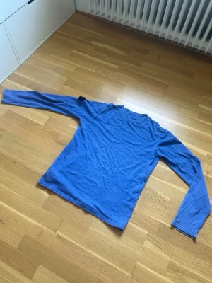 Stone Island blå tröja - Tjena, säljer nu en blå långärmad tröja från Stone Island med klassisk patch på vänster ärm. Tröjan har rund halsringning och är tillverkad i ett mjukt material som känns skönt mot huden. Perfekt för dig som gillar stilrena och ikoniska plagg. Två små slitningar vänster armen men inget som ses när du bär den.