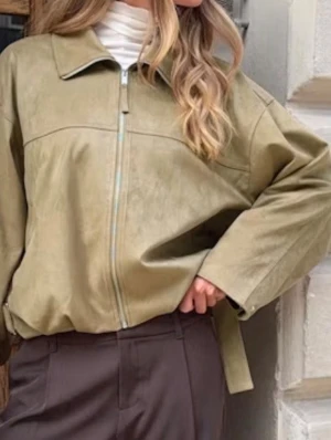 Olivgrön oversized jacka med dragkedja - Snygg oversized jacka i olivgrönt med dragkedja framtill och bred krage. Jackan har vida ärmar och en avslappnad passform. Materialet ser ut som mockaimitation vilket ger en trendig look. Perfekt att slänga över en hoodie eller polotröja.