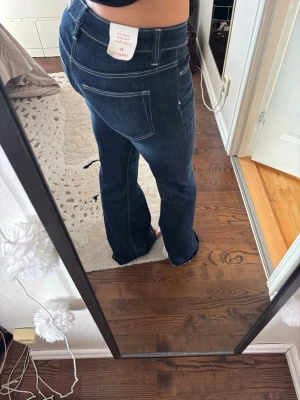 Mörkblå bootcut jeans - Snygga mörkblå bootcut jeans med vita kontrastsömmar. Jeansen är helt nya, aldrig använda!
