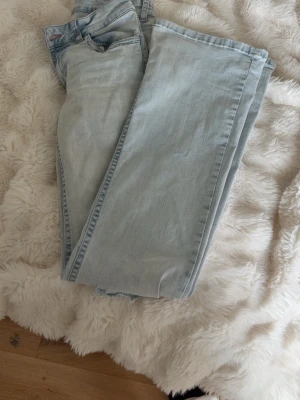 Ljusblå raka jeans - Säljer ett par ljusblå jeans med rak passform och klassisk femficksdesign. Jeansen har en enkel look utan slitningar eller dekorationer och är tillverkade i ett mjukt denimtyg. Perfekta för en avslappnad och stilren outfit.
