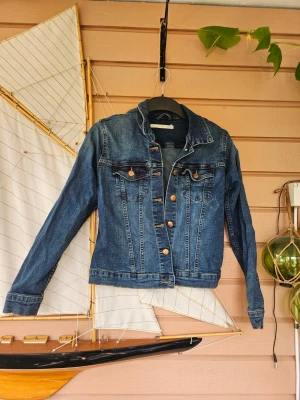 Klassisk blå jeansjacka - Snygg stretching mjuk och go klassisk blå jeansjacka med långa ärmar och knappar framtill. Två bröstfickor med lock och knappdetaljer. Perfekt att slänga över en hoodie eller t-shirt för en chill look.