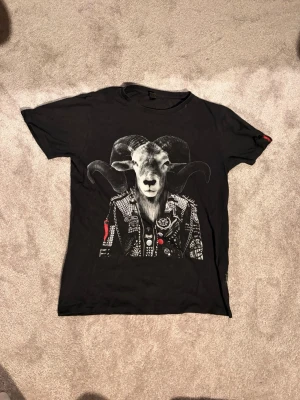 Svart t-shirt med tryck från Replay - Cool svart t-shirt från Replay med ett stort tryck av en bagge i rockig jacka på framsidan. T-shirten har klassisk passform och rund hals. Perfekt för dig som gillar unika och edgy motiv.