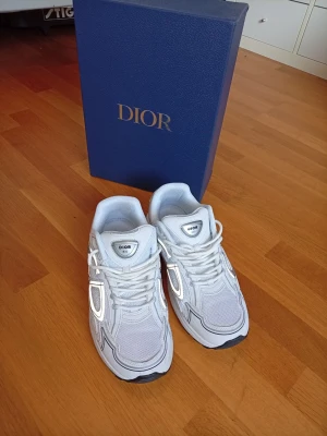 Vita Zara skor - Snygga vita sneakers med silvergrå detaljer och meshpaneler. Skorna har en chunky sula och klassisk snörning. Perfekt för dig som vill ha en exklusiv och trendig look.logga syns på sidan och plösen.