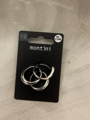 Silvriga ringar från Montini - Säljer ett par stilrena silvriga ringar från Montini.Ringer har en klassisk rund form och är tillverkade i metall med blank finish. Perfekta för dig som gillar minimalistisk och trendig stil.
