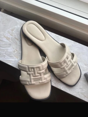 Tommy Hilfiger tofflor  - Super fina och BEKVÄMA Tommy Hilfiger tofflor i krämvit/ljusbeige färg!🤍 Nypris 1199kr Storlek 38 , normala i storlek! Skavanker: - Finns små skavanker kolla bilderna - Minimalt skav ( inget man tänker på) - Minimalt skav på sulan för man gått, inget som syns eller märks av