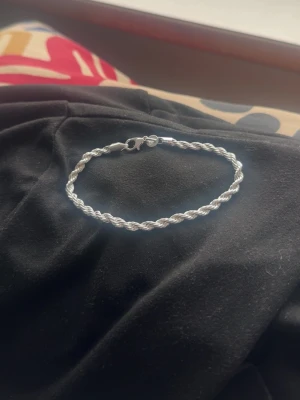 Silver armband - Stilrent armband i silverfärg med tvinnad design. Armbandet har en enkel karbinhake som lås och passar perfekt för dig som gillar minimalistiska accessoarer. Materialet ser ut som metall och armbandet har en klassisk, tidlös look.