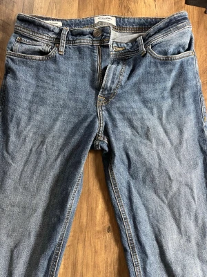 Jack & Jones Regular - Säljer ett par klassiska blå jeans från Jack & Jones i modellen Regular Clark. Jeansen har fem fickor, normal passform och snygga kontrastsömmar. Perfekta till vardagslooken och tillverkade i slitstarkt denimtyg.