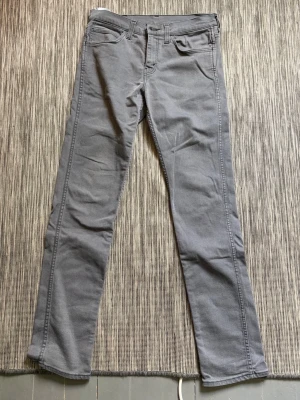 Gråa Levi's 511 slim jeans - Storlek 31 34. Snygga gråa Levi's 511 slim jeans med klassisk femficksdesign och normal midja. Jeansen har raka ben och är tillverkade i ett mjukt bomullsmaterial med lite stretch för extra komfort. Perfekta för en clean och stilren look.