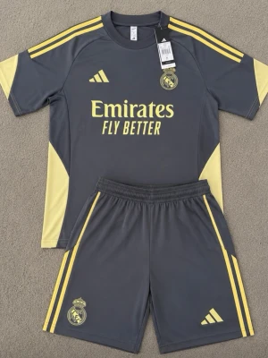 Real Madrid träningsset | M - Snyggt träningsset från Real Madrid i mörkgrått med gula detaljer. Hör av er vid funderingar, kan skicka fler bilder på detaljer. 