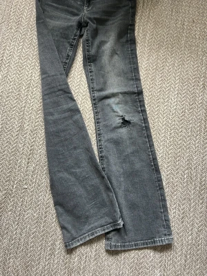 Svarta jeans med slitning - Snygga svarta jeans med tvättad look och slitning på ena benet. Klassisk femficksmodell med raka ben och normal passform. Perfekta för dig som gillar en lite tuffare stil.