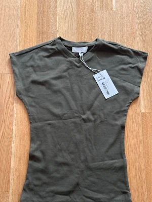 Mörkgrön t-shirt med korta ärmar - En stilren mörkgrön t-shirt i bomull med korta ärmar och rund hals. Passformen är normal och tyget känns mjukt och bekvämt. Perfekt till jeans eller shorts för en enkel och clean look.