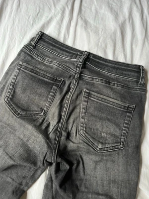 Grå bootcut jeans - Säljer ett par grå bootcut jeans med råa kanter nertill. Jeansen har klassisk femficksmodell och en tvättad look som ger en avslappnad vibe. 