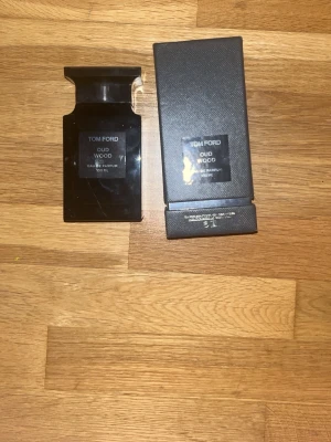 Tom Ford Oud Wood Eau de Parfum - Tom Ford Oud Wood Eau de Parfum 100 ml i elegant svart flaska med matchande svart kartong. Flaskan har en stilren, fyrkantig form och etikett framtill. En exklusiv doft med lyxig känsla, perfekt för dig som gillar unika och djupa parfymer.