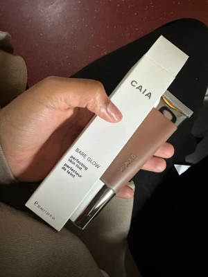 CAIA Bare Glow foundation - CAIA Bare Glow Perfecting Skin Tint foundation i en beige nyans. Kommer i en stilren tub med silvrig kork och rymmer 30 ml. Ger en naturlig glow och lätt täckning, perfekt för en fräsch look. Enkel att applicera och passar dig som gillar en naturlig finish. OBS! Köpt i fel färg öppnad men aldrig testad. Färgen är 50 och köpt för 345kr
