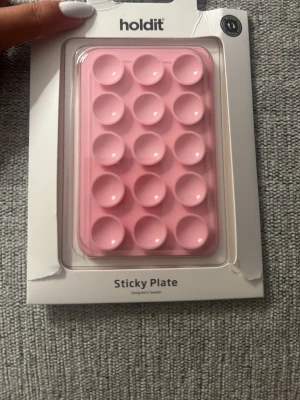 Holdit rosa Sticky Plate med sugproppar - Säljer en rosa Sticky Plate från Holdit med flera sugproppar. Perfekt för att fästa mobilen på släta ytor, t.ex. för selfies eller videosamtal. Passar MagSafe-kompatibla skal och har en magnetisk baksida. Designad i Sverige och veganvänlig. Endast öppnad och ej använd då den ej funkar för min telefon
