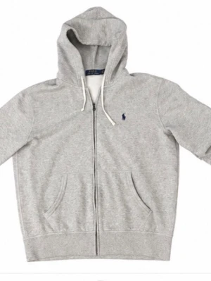 Ralph Lauren grå zip-hoodie - Snygg grå hoodie med dragkedja och huva, från Polo Ralph Lauren. Broderad marinblå logga på bröstet, vita snören i huvan och två fickor framtill. Mjuk bomullsblandning som är perfekt för en avslappnad stil.