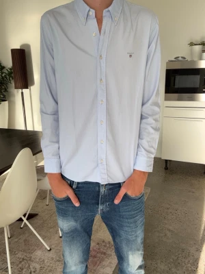 Ljusblå klassisk skjorta från gant - Snygg ljusblå skjorta med button-down krage och diskret broderad logga på bröstet. Skjortan har långa ärmar och vita knappar framtill. Perfekt till jeans eller chinos för en clean och stilren look. Storlek 170 passar upp till 175. Har en till, finns en andra annons ifall man vill köpa 2x