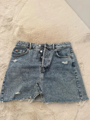Jeanskjol  - Jeanskjol från Bershka – strl 36 💙  Säljer en supersnygg ljusblå jeanskjol från Bershka i storlek 36. Endast använd 1 gång, så den är i nästan nyskick utan anmärkningar. Trendig modell med slitna detaljer och rå fransad kant nedtill – perfekt till sommaren!  📏 Storlek: 36 (S) 👖 Märke: Bershka ✨ Skick: Använd 1 gång, mycket fint skick.  Skicka gärna ett meddelande om du har frågor eller vill ha fler bilder! 😊
